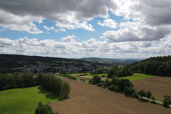 Felder, Wiesen und Waldstücke rund um Langendernbach aus der Luft, im Hintergrund die Ortsbebauung.