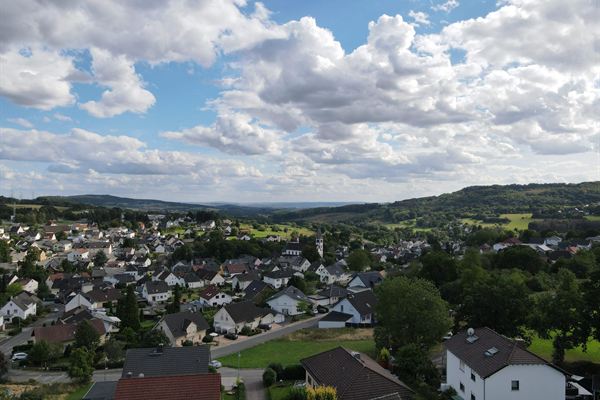 Luftbild über die Ortsmitte mit Blick auf die Hügel am Horizont