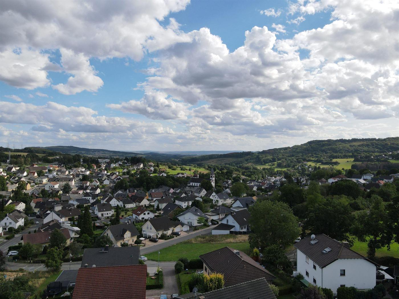 Luftbild über die Ortsmitte von Langendernbach mit Blick auf die Hügel am Horizont.