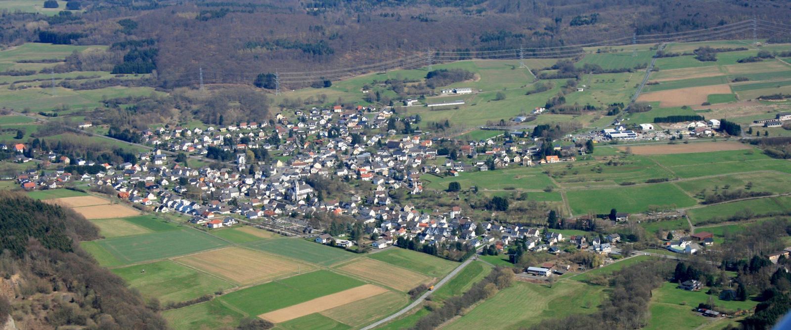 Luftaufnahme von Langendernbach: der Ort liegt zwischen Feldern und bewaldeten Hügeln im Elbbachtal.