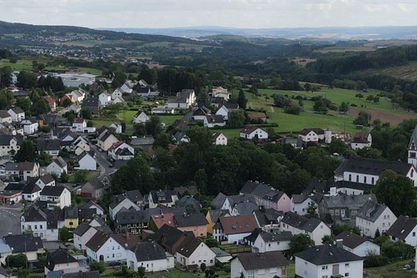 Ortspanorama vor bewaldeten Höhenzügen
