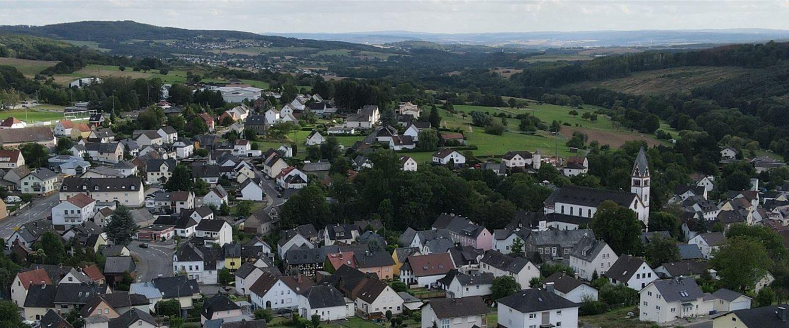 Panorama von Langendernbach vor bewaldeten Höhenzügen.